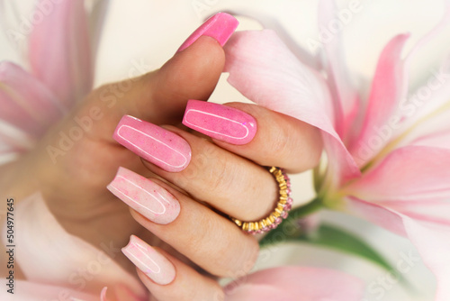 Fotografija Pink elongated nail extension with fine glitter.