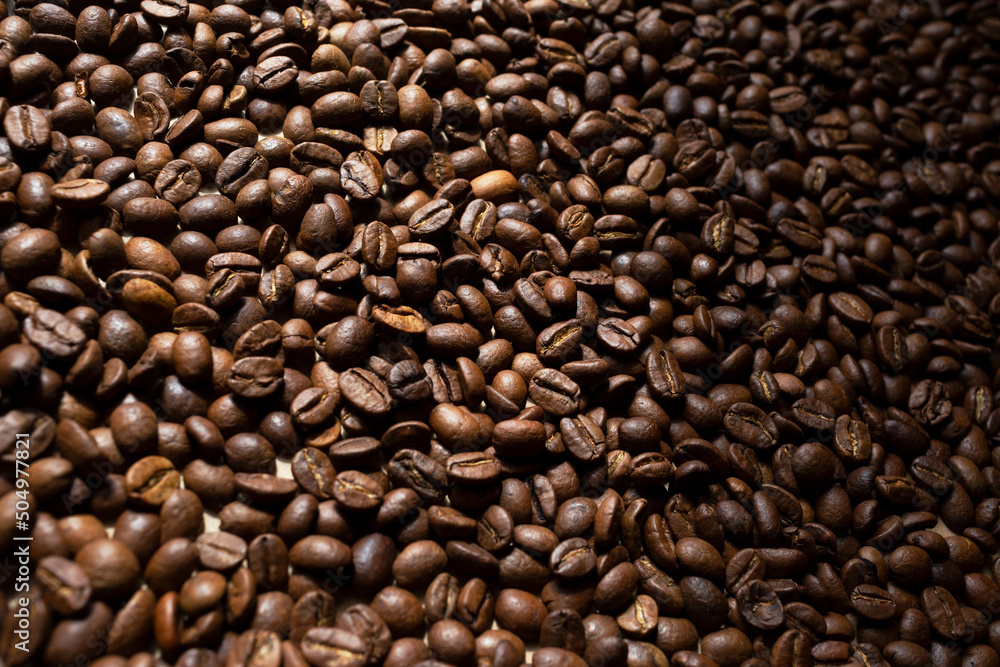 Roasted coffee beans texture. Top view, flat lay. Place for text. Copy space. Rays of the sun shine on the coffee beans. Roasted coffee beans texture. Top view, flat lay. Place for text. Copy space. Rays of the sun shine on the coffee beans.
