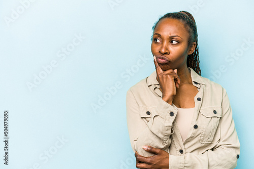 Tableau sur toile Young african american woman isolated on blue background looking sideways with doubtful and skeptical expression