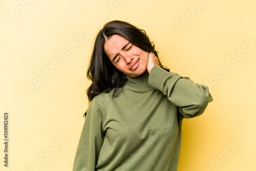 Young hispanic woman isolated on yellow background suffering neck pain due to sedentary lifestyle. © Asier