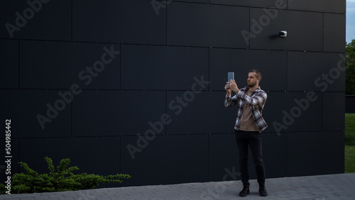 A man works with a tablet in the park near office buildings