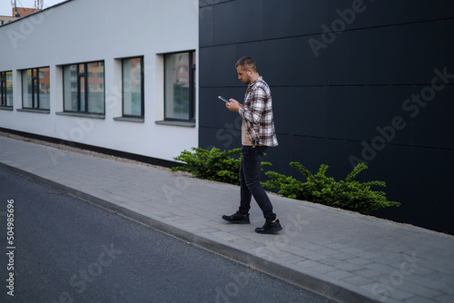 A man works with a tablet in the park near office buildings