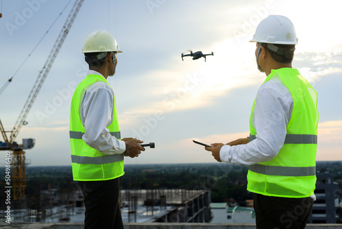 Two engineering working by controll drone on construction site. 
