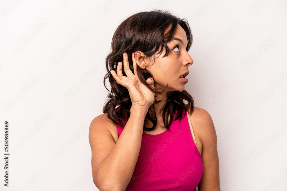Young hispanic woman isolated on white background trying to listening a gossip. Young hispanic woman isolated on white background trying to listening a gossip.