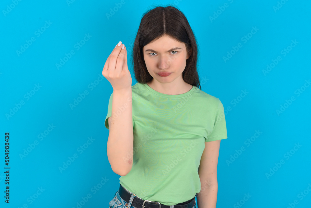 Fototapeta premium young beautiful Caucasian woman wearing green T-shirt over blue wall Doing Italian gesture with hand and fingers confident expression