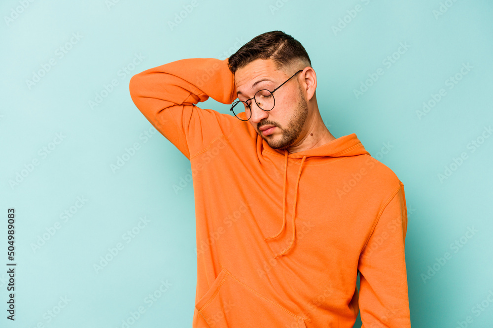 Young hispanic man isolated on blue background tired and very sleepy keeping hand on head. Young hispanic man isolated on blue background tired and very sleepy keeping hand on head.