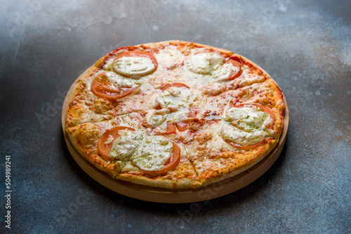 Italian pizza Margherita buffalo with tomatoes, mozzarella and cheese with tomato sauce on wooden board on dark blue stone table