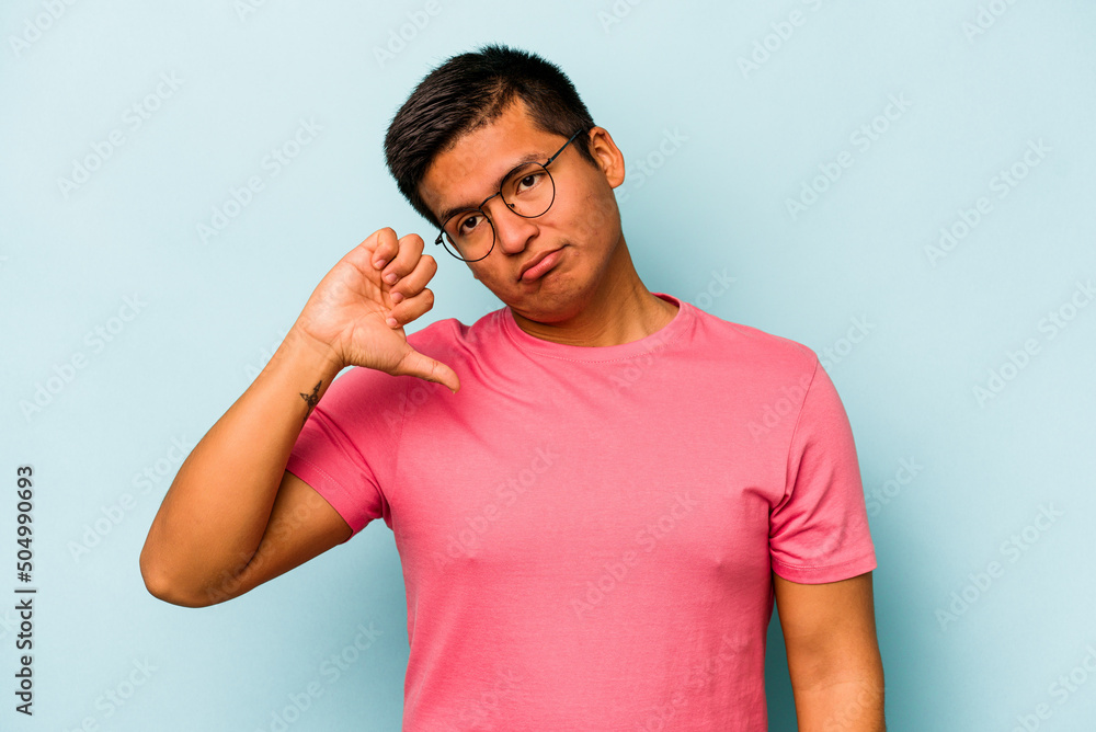 Young hispanic man isolated on blue background showing a dislike gesture, thumbs down. Disagreement concept. Young hispanic man isolated on blue background showing a dislike gesture, thumbs down. Disagreement concept.
