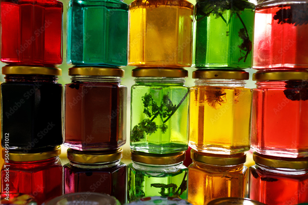 Multicolored honey in a jar on the counter. Colored jars with sweet honey or jam Multicolored honey in a jar on the counter. Colored jars with sweet honey or jam