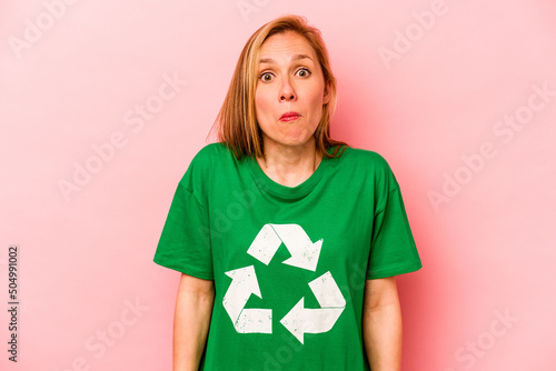 Fotografia Young volunteer woman isolated on pink background shrugs shoulders and open eyes confused