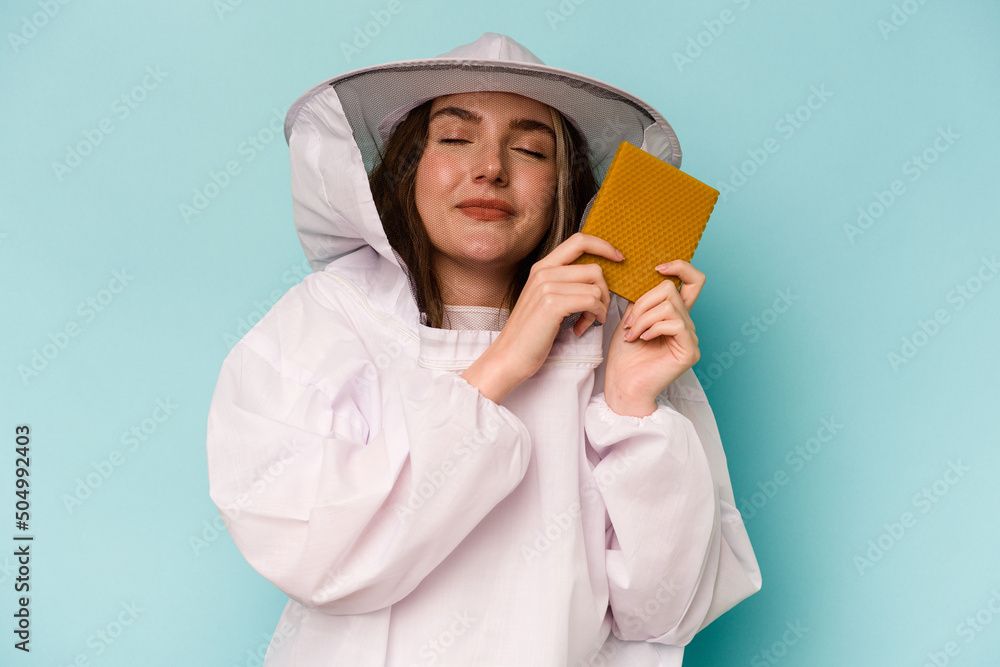Young caucasian beekeeper woman isolated on blue background Young caucasian beekeeper woman isolated on blue background