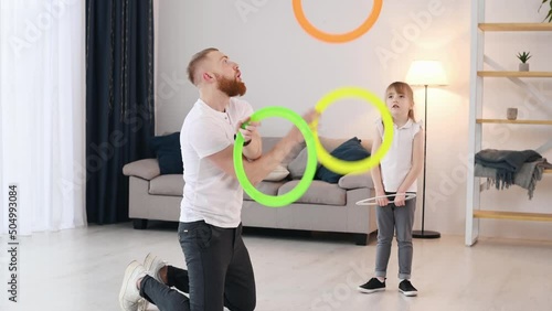 Man showing jugglery by using colorful cirlces. Father with his little daughter is at home indoors