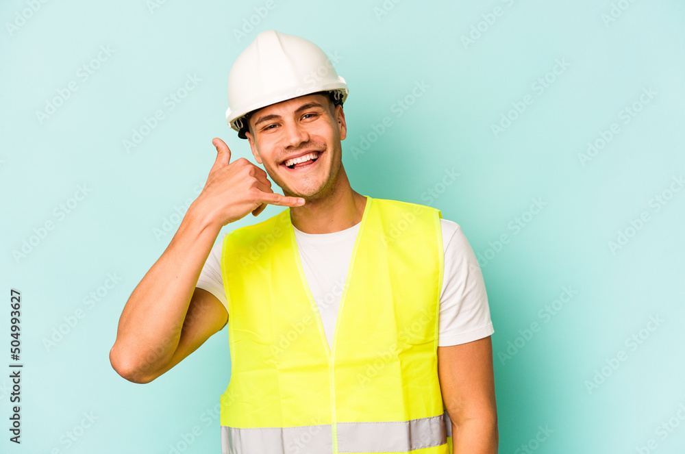 Young laborer caucasian man isolated on blue background showing a mobile phone call gesture with fingers.