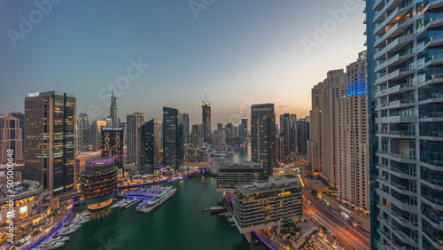 Aerial view to Dubai marina skyscrapers around canal with floating boats day to night timelapse