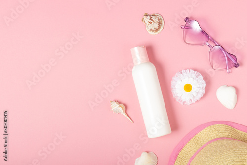 Children's sunscreen, sunglasses accessories and jewelry on a pink background. Cosmetics and accessories for little girls, flat lay. Summer baby cosmetics