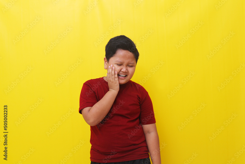 Asian boy feel pain in the teeth. Healthy concept. Isolated on yellow background Asian boy feel pain in the teeth. Healthy concept. Isolated on yellow background