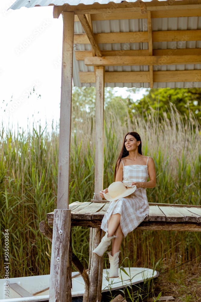 Φωτογραφία Young woman relaxing on the wooden pier at the calm lake
