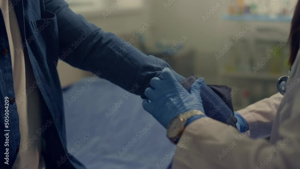 Woman doctor putting cuff measuring blood pressure on old man arm close up. Woman doctor putting cuff measuring blood pressure on old man arm close up.