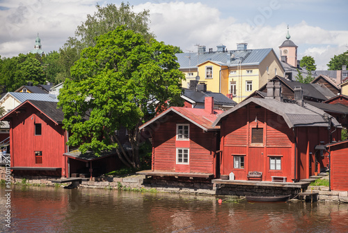 Old red wooden houses and barns stand along the river coast in old town