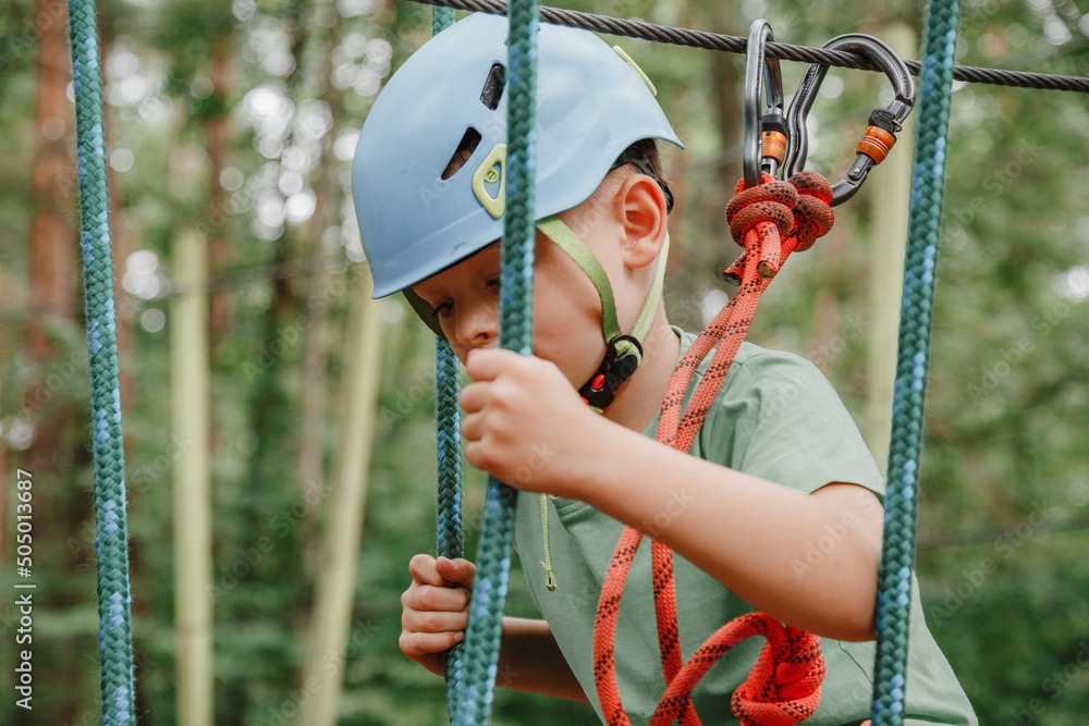 Brave little boy having fun at adventure park and smiling to camera ...