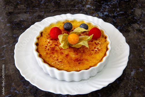 Obraz na plátně Traditional crème brûlée in a porcelain ramekin decorated with red fruits
