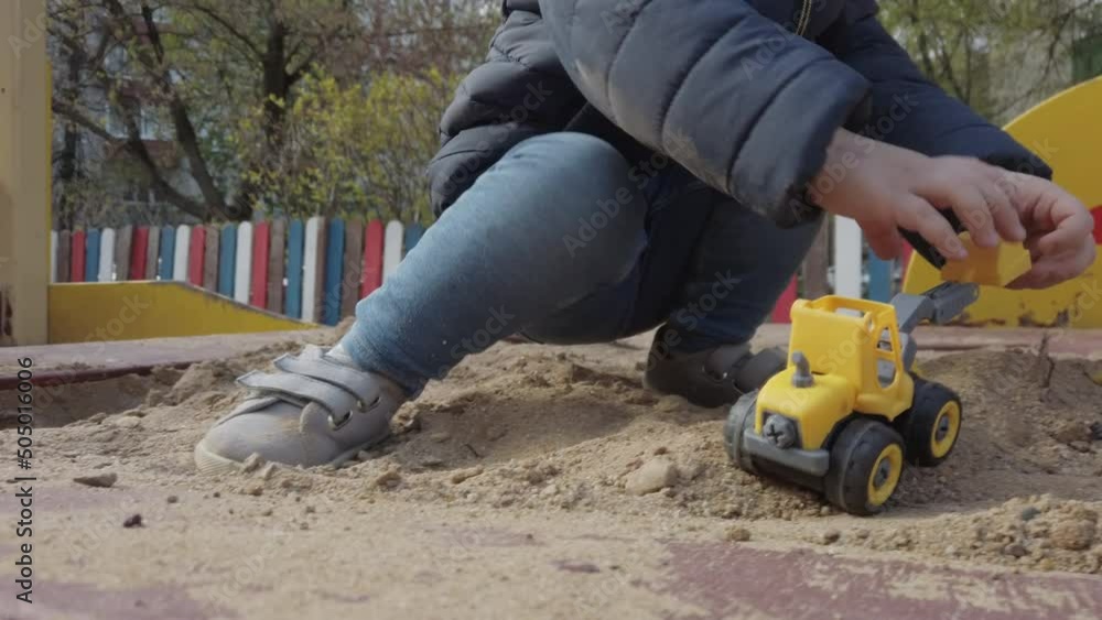 Toddler kid playing with toy car in sandbox. Toddler kid playing with toy car in sandbox.