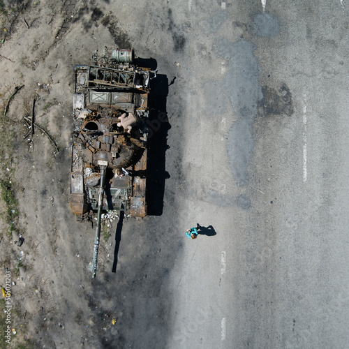 Kyiv region, Ukraine - May 15, 2022: War in Ukraine. Highway Kyiv - Zhytomyr. People take selfies against destroyed russian tank after russian atack in Febrary. photo