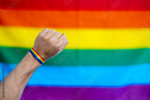 Puño alzado por la reivindicación de los derechos del colectivo lgtbi, con la bandera arcoíris de fondo 