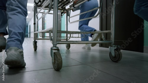 Doctors feet running down hospital corridor. Medical team moving gurney.