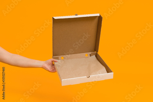 open empty pizza box in hand on color background