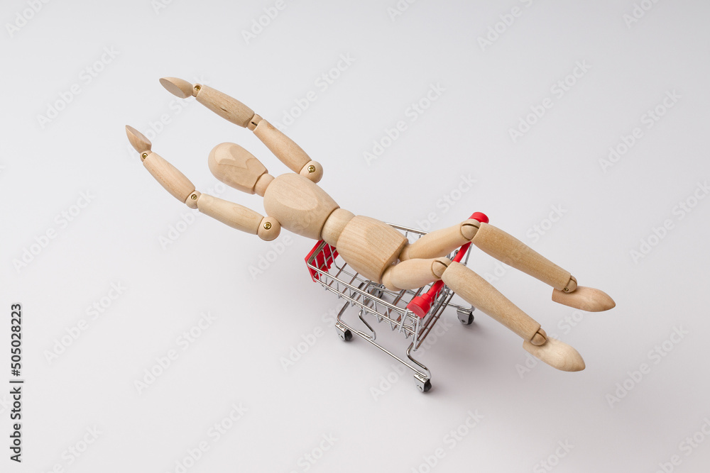 a wooden man lies in a cart from a supermarket and quickly rides in it like a rocket, white background