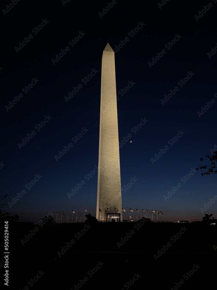 The Washington Monument at night with the moon shot from the National Mall.