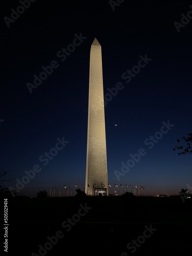 The Washington Monument at night with the moon shot from the National Mall.