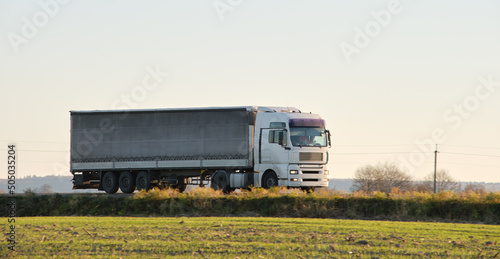 Semi-truck with cargo trailer driving on highway hauling goods in evening. Delivery transportation and logistics concept