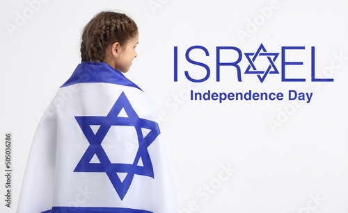 Little girl with flag and text ISRAEL INDEPENDENCE DAY on light background photo