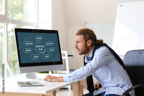 Businessman with computer making a marketing plan in office