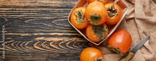 Ripe persimmons on wooden background with space for text photo