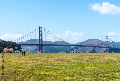 Dramatic image of the Golden Gate Bridge in San Francisco, California from Crissy field, with green grassy field in the foreground.