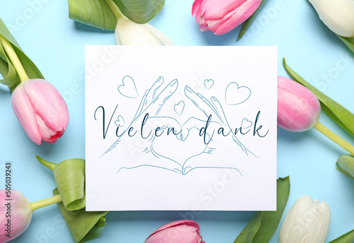 Card with text VIELEN DANK (German for Thanks a lot) and tulip flowers on light blue background photo