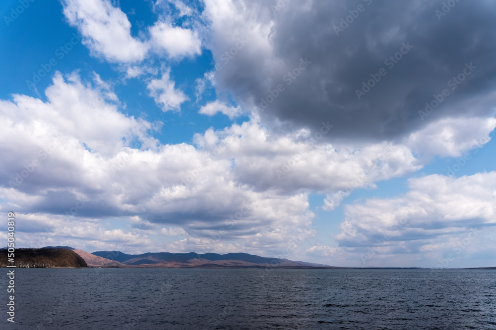 Dark blue clouds and sea or ocean water surface with dramatic seascape
