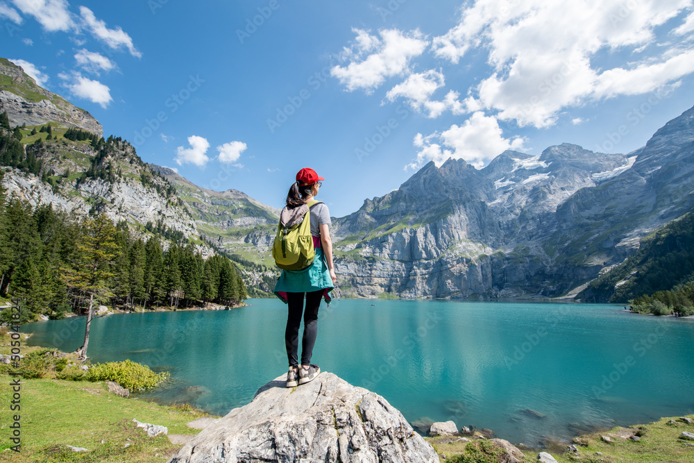 Young woman hiking near Oeschinensee (Oeschinen Lake) in summer, Kandersteg, Switzerland - obrazy, fototapety, plakaty 