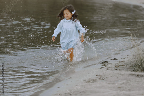 Fototapeta Naklejka Na Ścianę i Meble -  Adorable curly baby girl splashing in a river