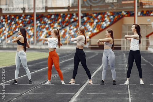 Five sports girls in a uniform training at the stadium