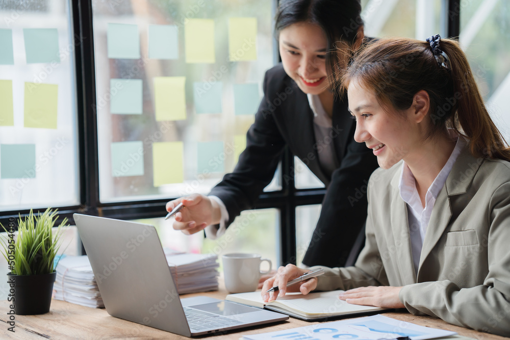 Two young asian business woman working together in office space, brainstorm sharing ideas concept.