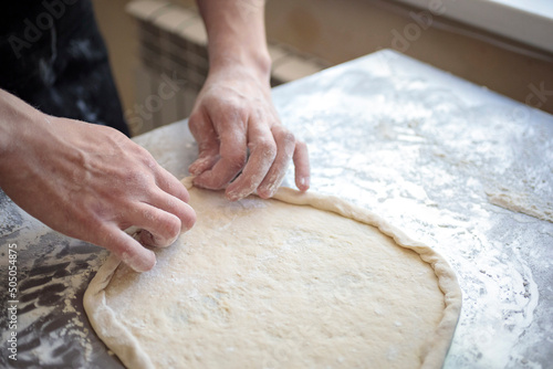 hands of the cook kneading pizza dough close-up