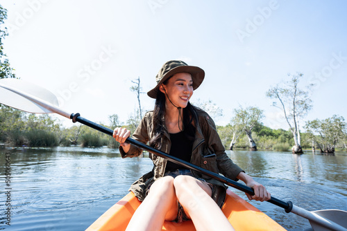 Asian young attractive tourist woman rowing kayak alone in forest lake
