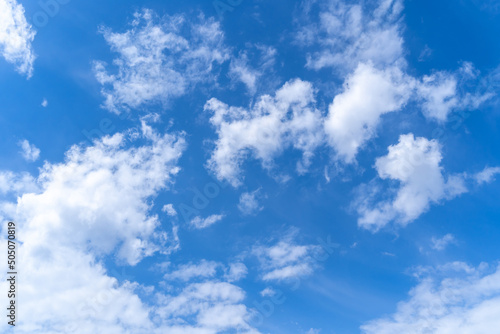 Blue sky background with white fluffy clouds. Clear weather, a feeling of freedom and vitality.