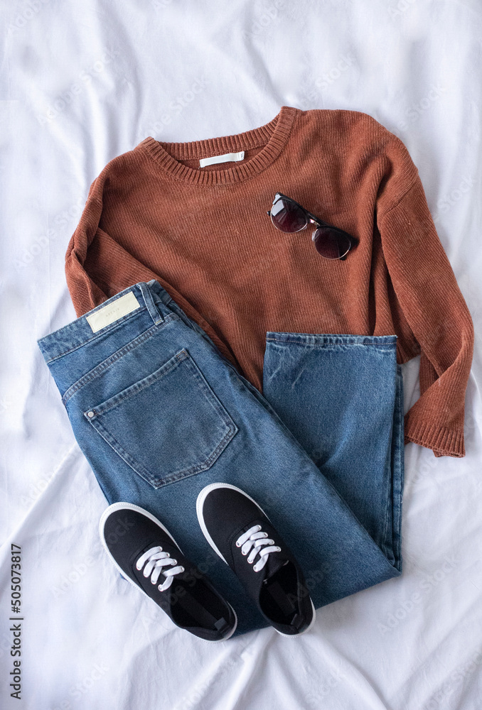 Clothing women flat lay with blue jeans, brown sweater, black sneakers and  sunglasses on white Stock Photo | Adobe Stock