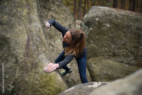 blonde woman rock climbing in forest