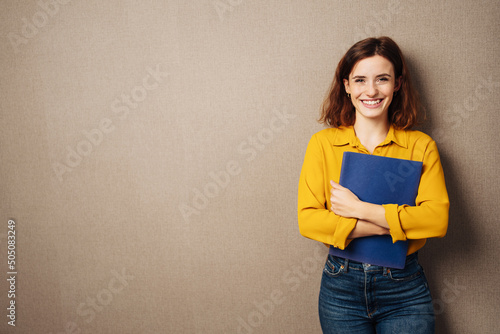 Laughing young woman against a brown background with her application documents in her hands photo